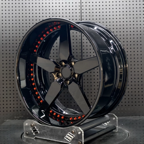 Reflective black three-spoke forged wheel displayed in a workshop setting