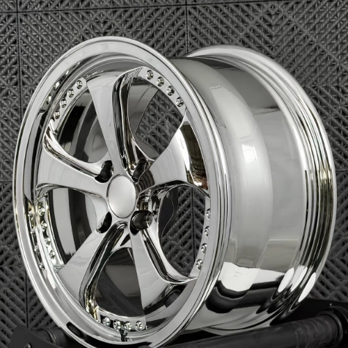 Chrome electroplated five-spoke wheel with decorative bolts displayed in a workshop