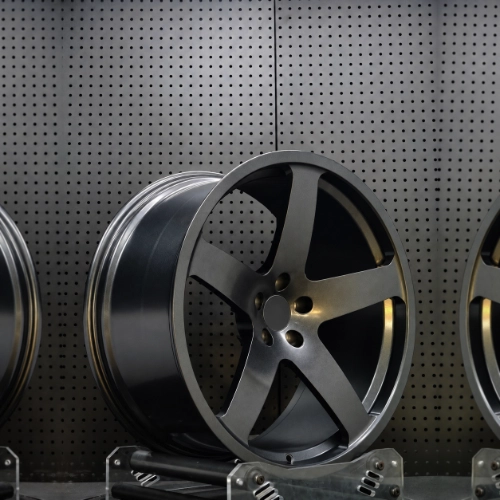 Three-quarter workshop view of matte gunmetal forged wheel with recessed center and rim depth